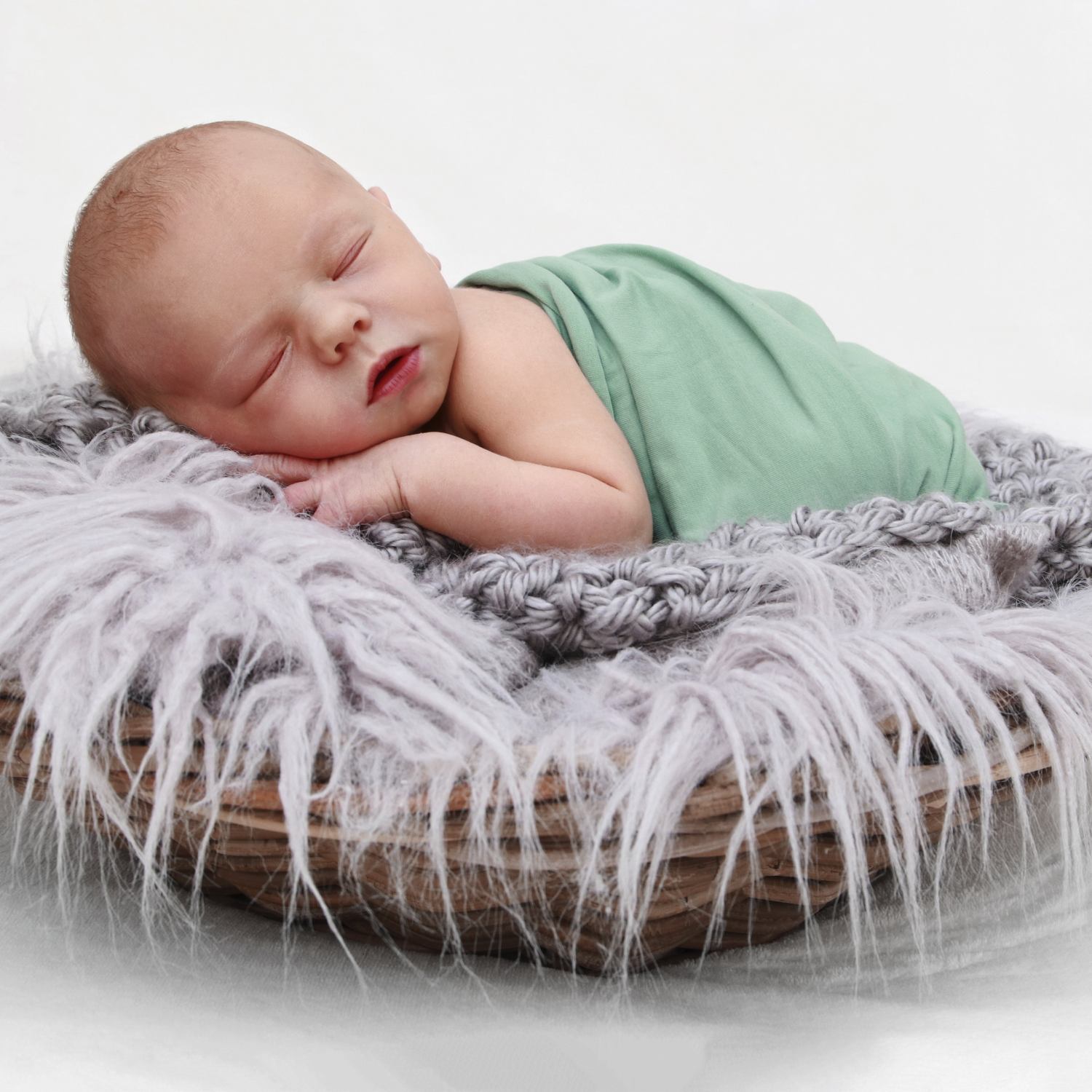 In ein Tuch eingewickeltes Neugeborenes schläft in einem Körbchen