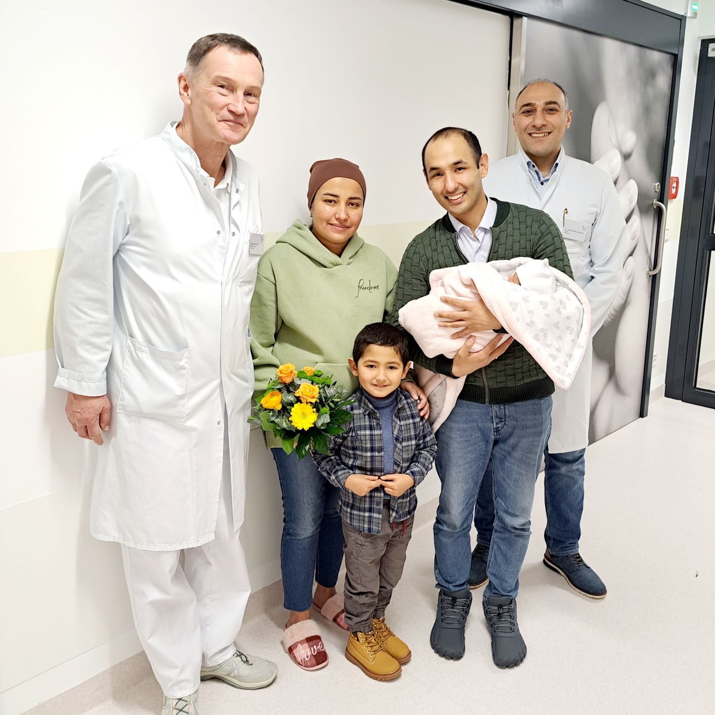 Foto vom Neugeborenen Baby mit den Eltern und Chefarzt Dr. Seropian sowie Oberarzt Andreas Kuznik